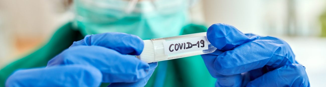 Close-up of epidemiologist with COVID-19 sample in test tube.